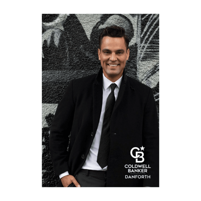 A professional headshot of Matthew Konsmo in a black coat and tie, standing in front of an abstract black-and-white mural. The logo for Coldwell Banker Danforth is displayed in the bottom right corner